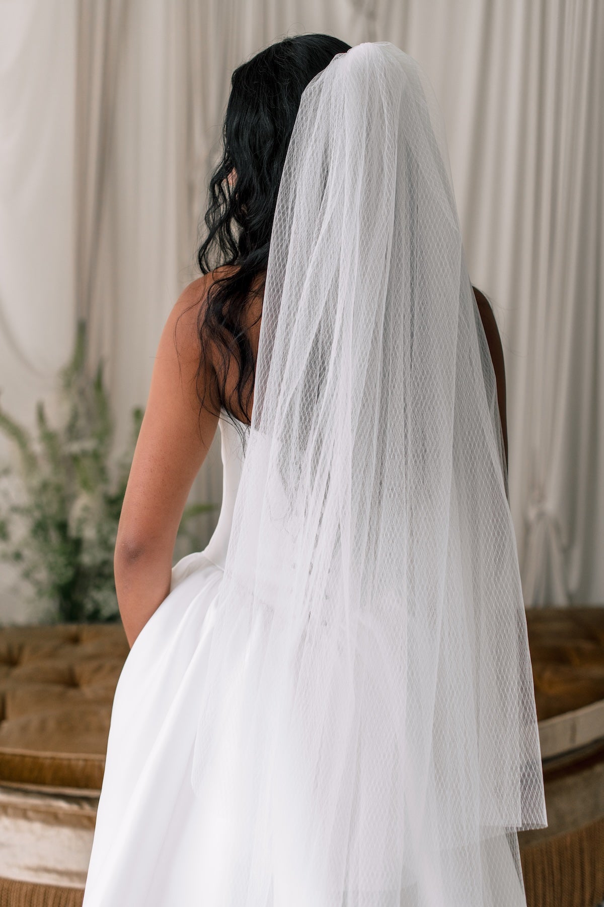 Bride wearing a long white veil with a neutral background
