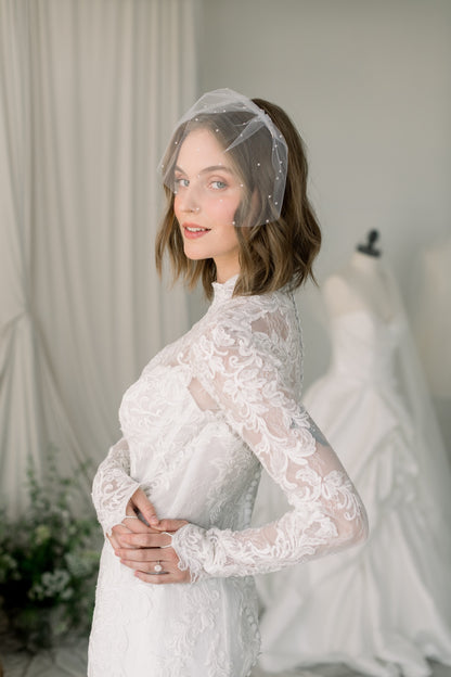 Woman wearing a white lace dress with a veil in a bridal setting