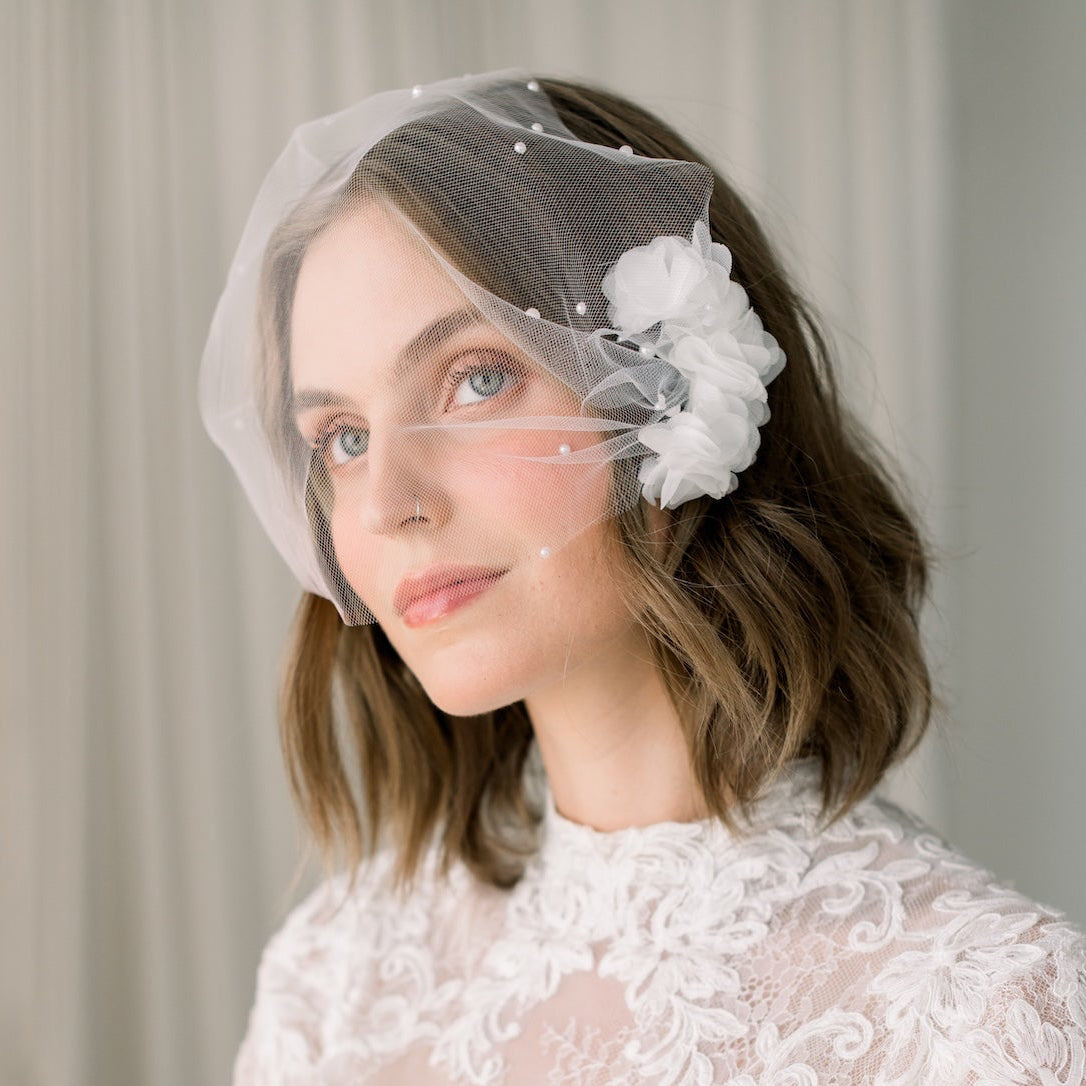 Woman wearing a lace wedding dress and veil with floral accents.