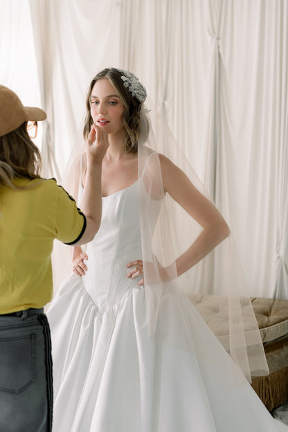 Woman in a white wedding dress being assisted by a person in a yellow shirt.