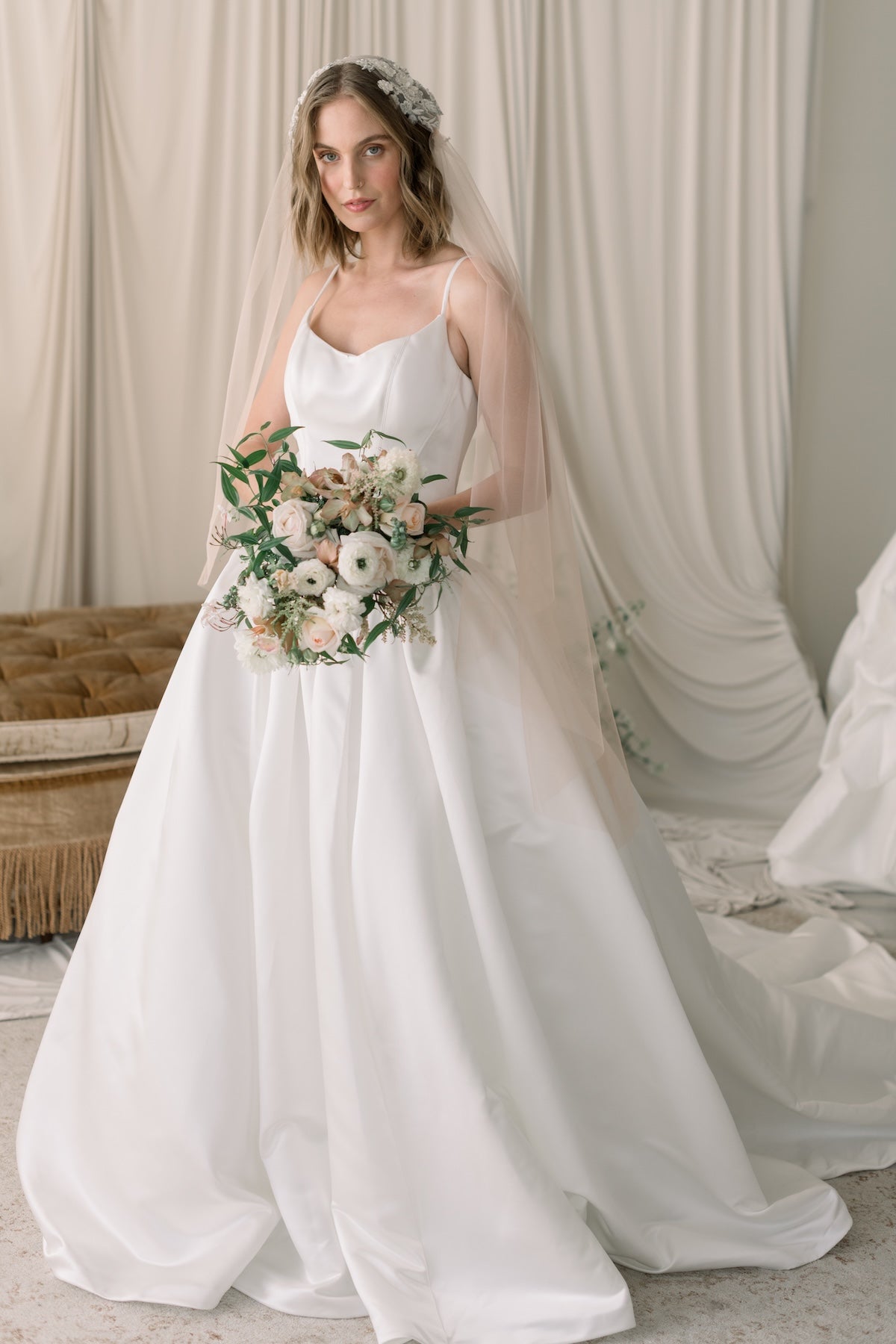 Woman in a white wedding dress holding a bouquet in a softly lit room.