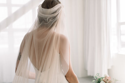 Person wearing a beige veil in a softly lit room