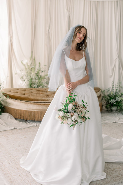 Bride in a white wedding dress holding a bouquet in a decorated room.