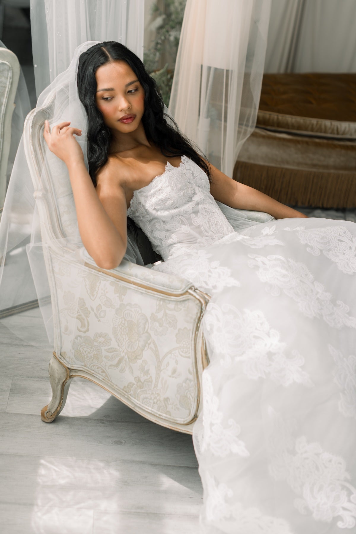 Woman in a white wedding dress sitting on a decorative chair.