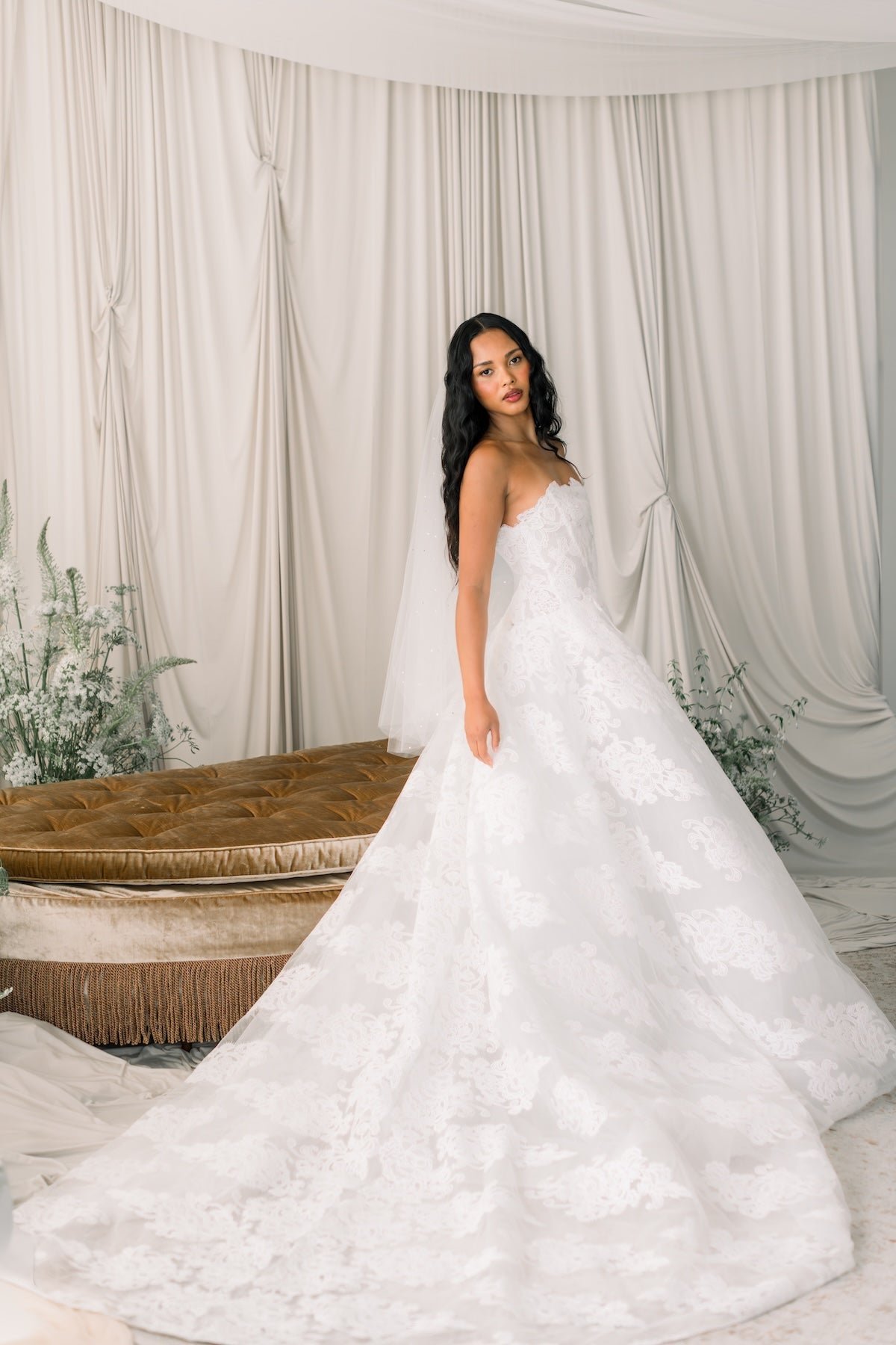 Woman in a white wedding dress standing in front of a draped curtain