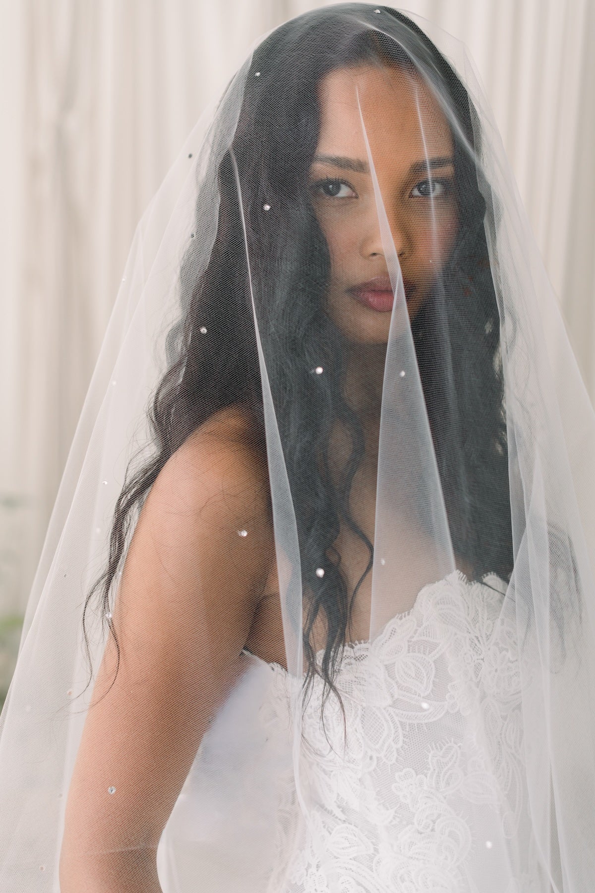 Woman wearing a white wedding dress with a veil indoors