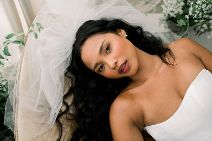 Woman in a white dress with a veil, surrounded by greenery