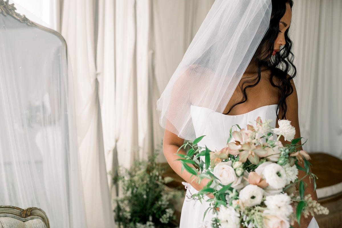 Bride holding a bouquet of flowers in a softly lit room.