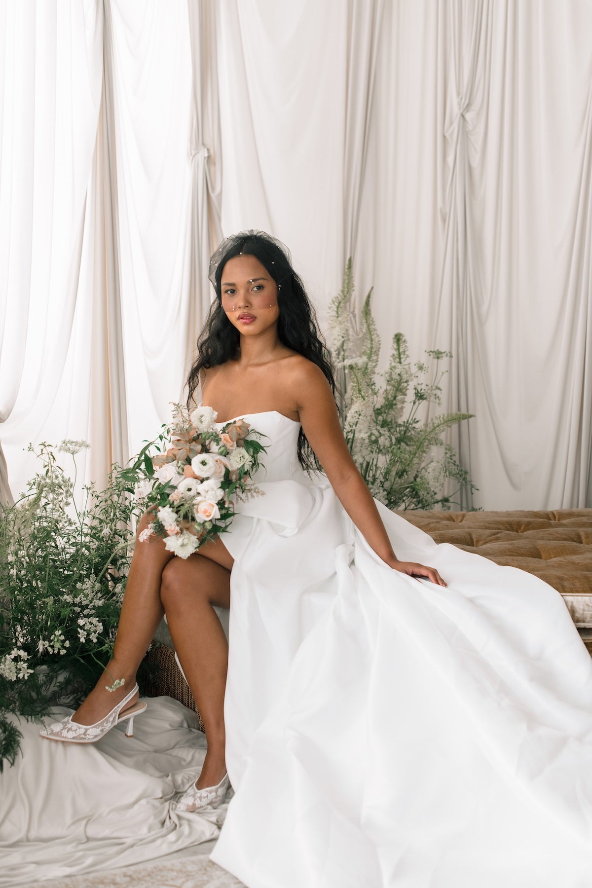 Woman in a white wedding dress holding a bouquet of flowers in a decorated room.