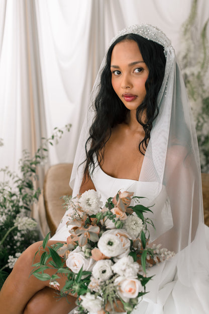 Bride holding a bouquet of flowers with a white veil and floral decorations.