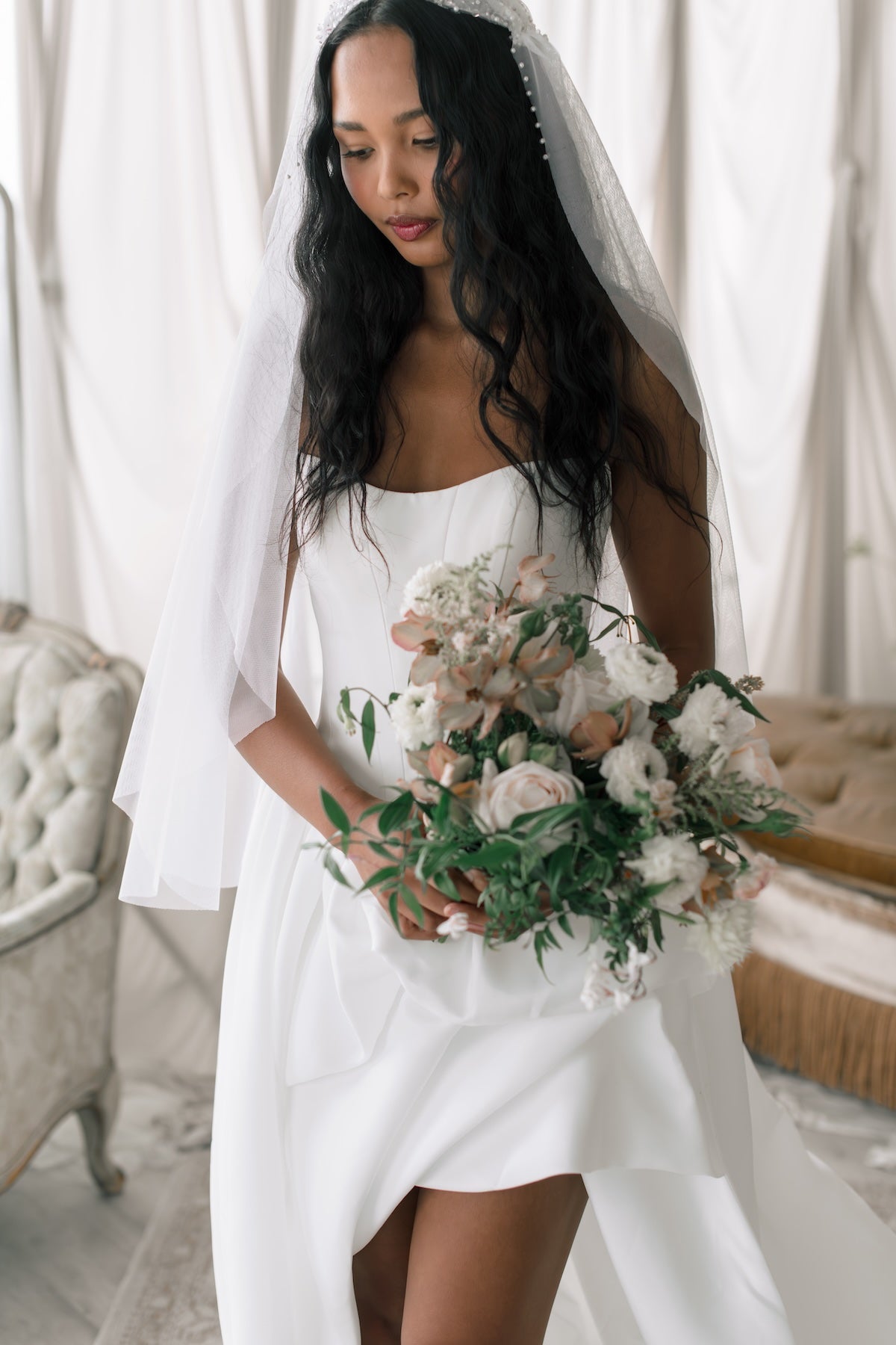 Bride in a white dress holding a bouquet of flowers with a veil.