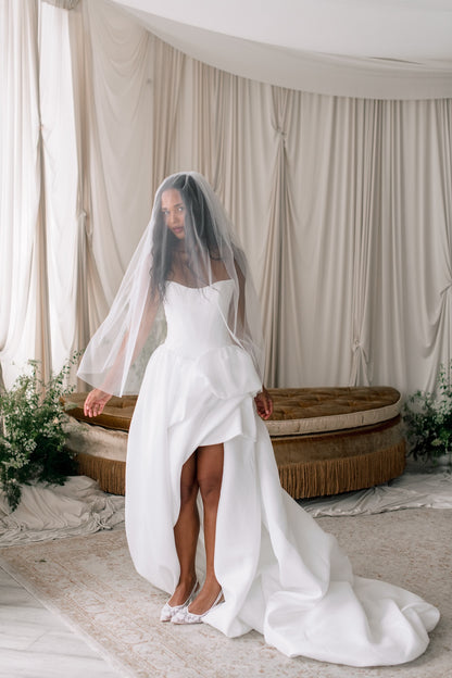 Woman in a white wedding dress with a veil standing in a decorated room.