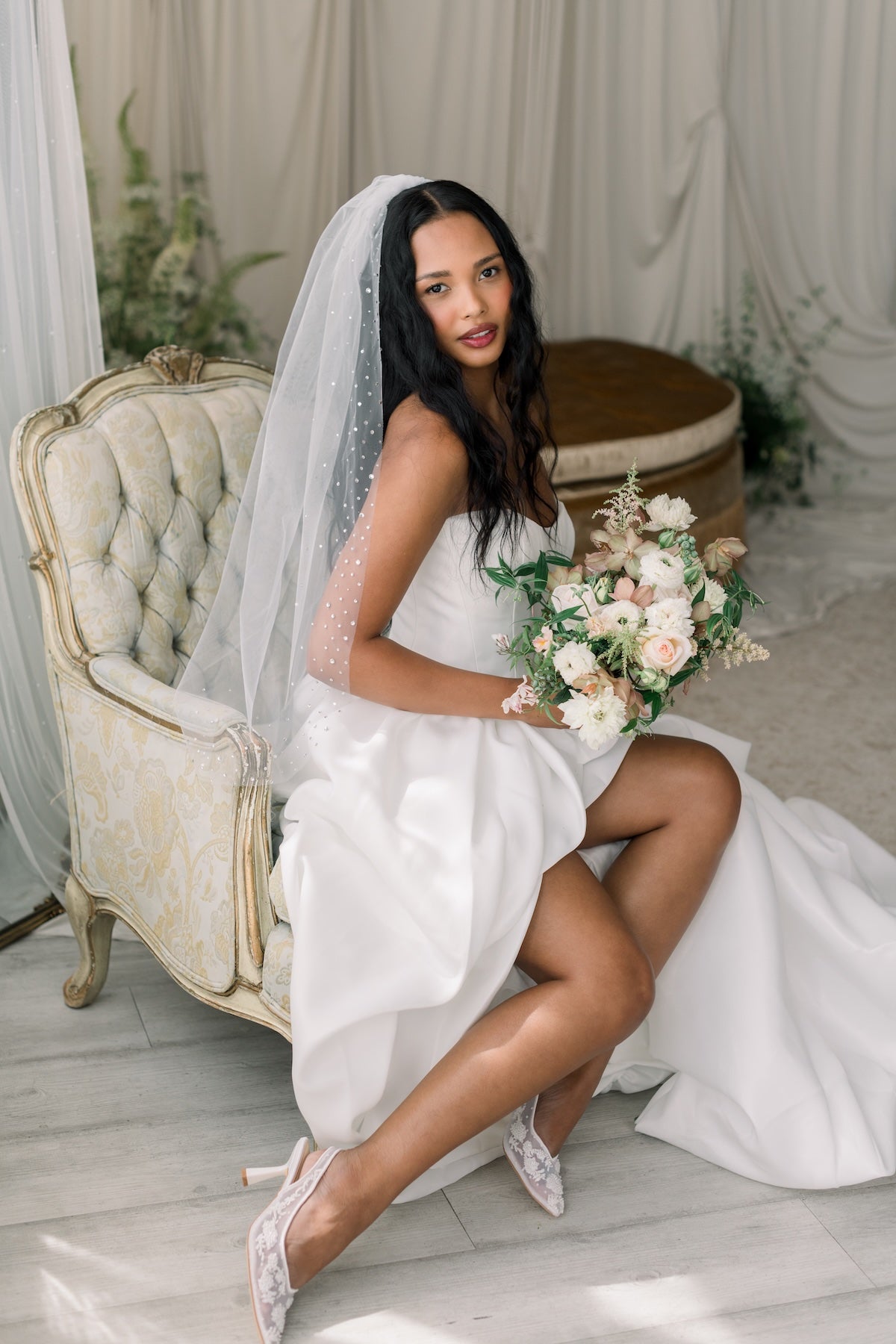 Woman in a wedding dress holding a bouquet in a decorated room.