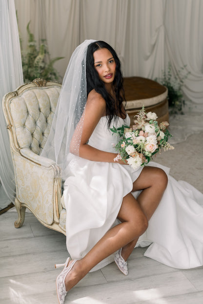 Woman in a wedding dress holding a bouquet in a decorated room.