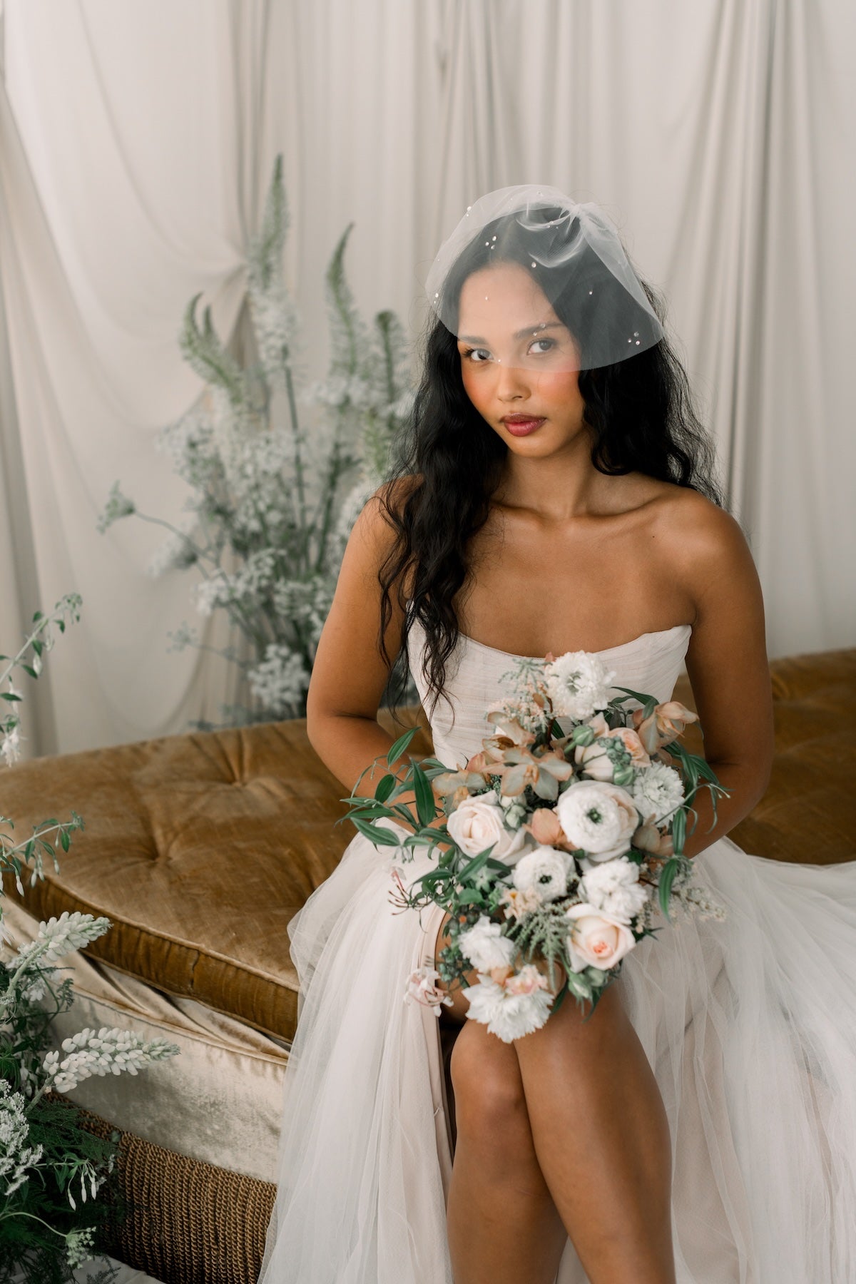 Woman in a white wedding dress holding a bouquet with a neutral background