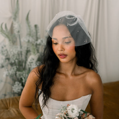 Bride holding a bouquet with a veil and floral background